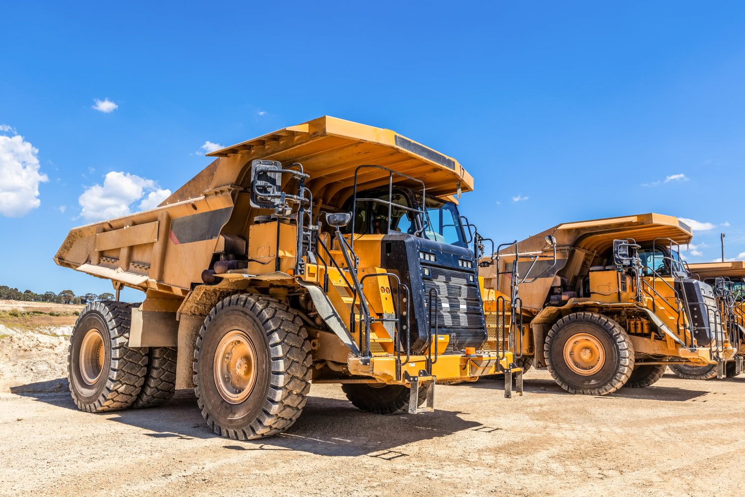 Yellow dumper trucks in a quarry on hot sunny day